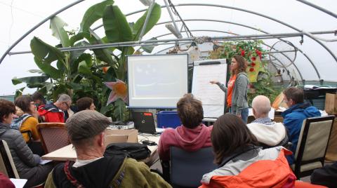 Students gather around a presentation with plants in the background