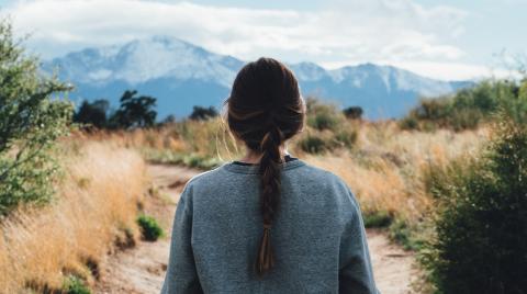 Woman facing a trail with moutains in the background