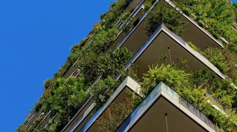Building with green plants at every level against a blue sky.