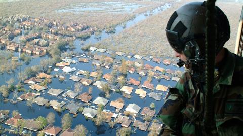 Soldier in helicopter overlooking flooded community