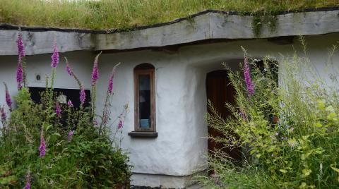 White house with a green roof and bushes in front