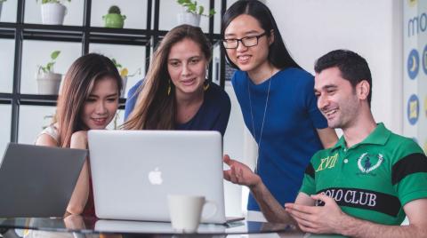 Four people in an office holding an online meeting