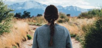 Woman facing a trail with moutains in the background