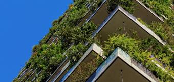 Building with green plants at every level against a blue sky.