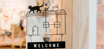 Welcome sign in the outline of a house with a cat on top