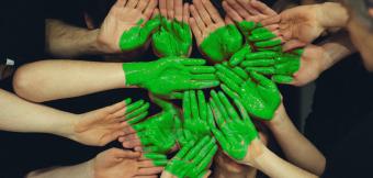 Hands being painted into a green heart