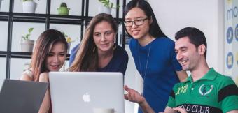 Four people in an office holding an online meeting