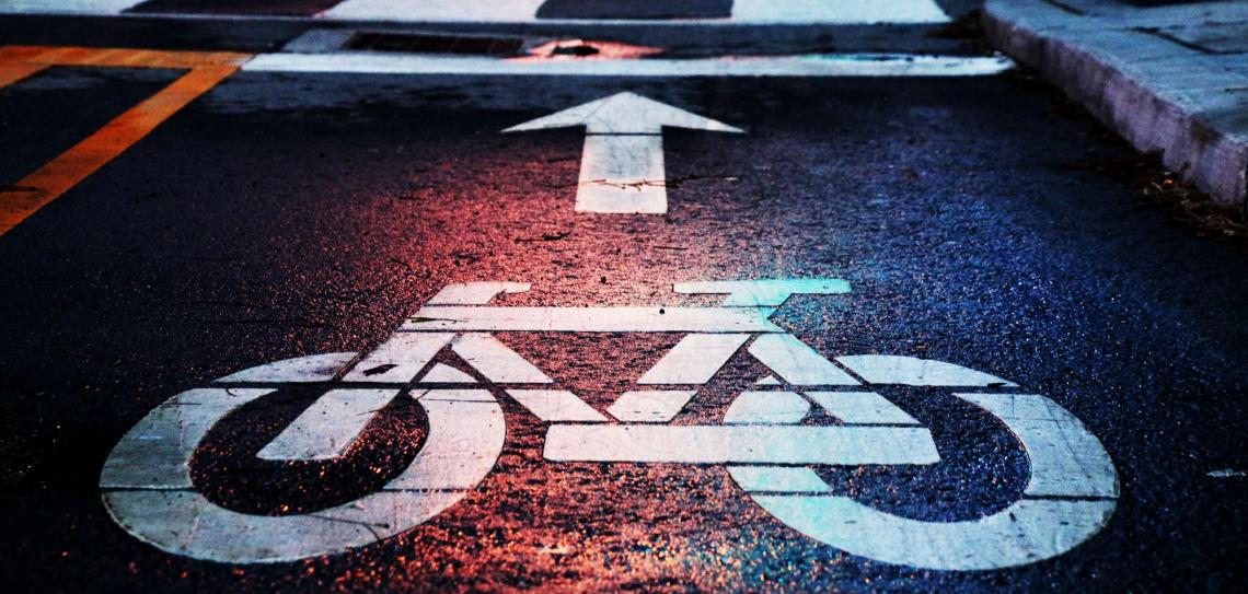 Cycling is the way forward! Photo by Andrew Gook on unsplash.com A bicycle road marking with a large 'forward' arrow