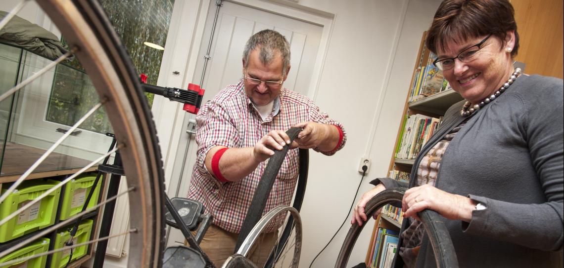 Repair cafes are places to meet and learn how to fix your broken items. Photo: Martin Waalboer/Repair Café International Foundation Man and woman at a repair cafe fixing a bike