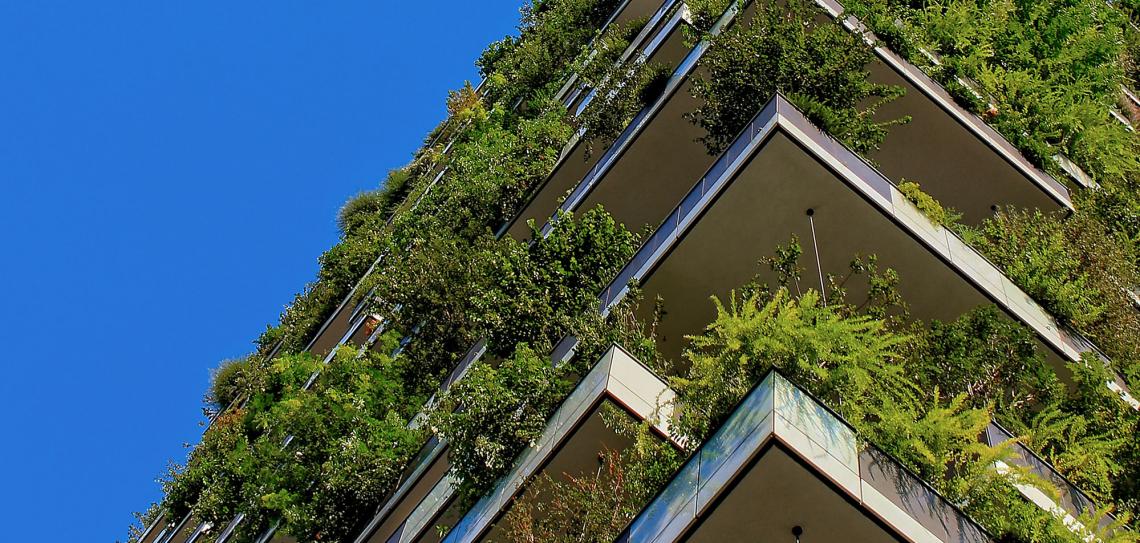 Building with green plants at every level against a blue sky.