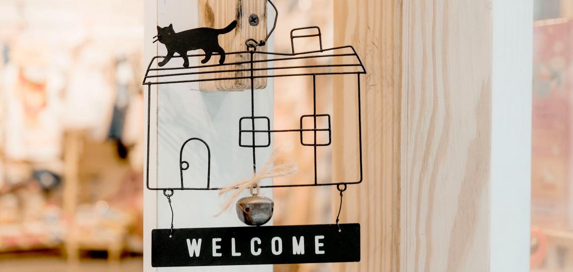 Welcome sign in the outline of a house with a cat on top