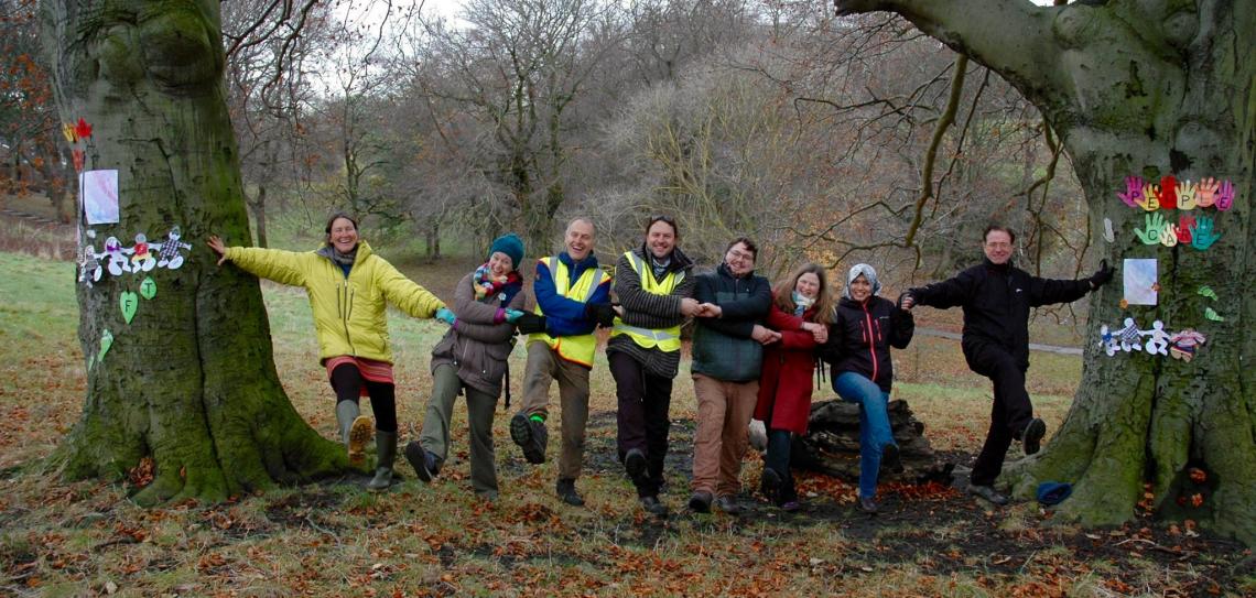 Social benefits including increased social capital, civic participation and inclusion. Photo: Sunderland Local Ambassadors Gathering - Flickr.com/permaculture-association People standing holding hands between two trees