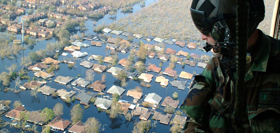 Soldier in helicopter overlooking flooded community