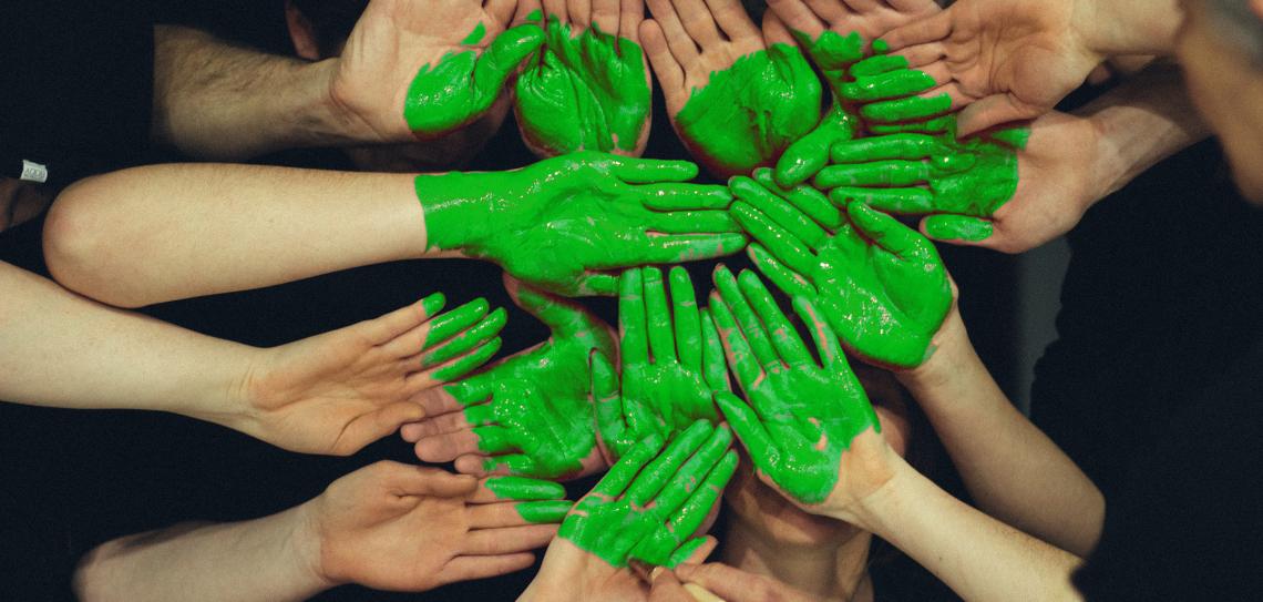 Hands being painted into a green heart