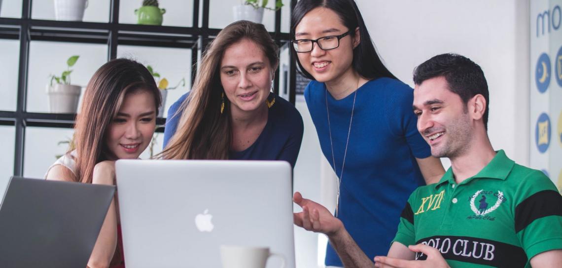 Meeting up with faraway colleagues online rather than face-to-face is a great way to reduce emissions. Photo: Mimi Thian - Unsplash.com Four people in an office holding an online meeting