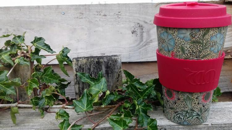 Carrying a reusable cup with you cuts down on the need for disposable alternatives. Photo: Sarah Cossom Reusable coffee cup on a wooden fence with ivy