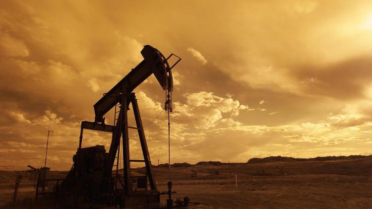 Oil being drilled from the earth with desert landscape behind it