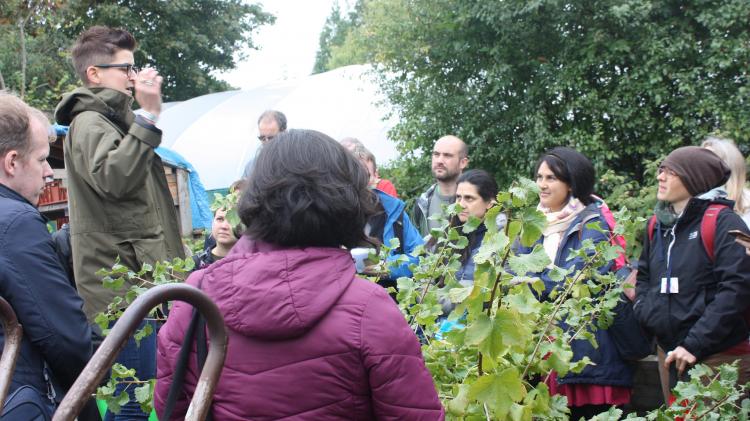 Person leading a Permaculture Session to a group in an outdoor garden setting