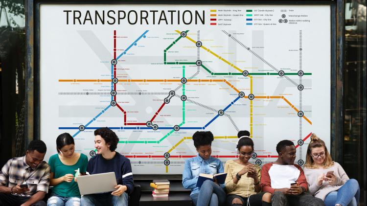 Several people sitting on a bench in front of a transportation map.
