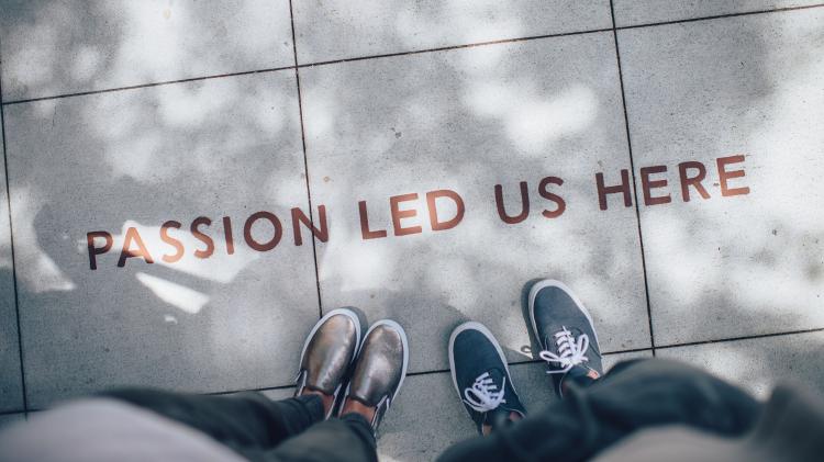 If existing adaptation strategies are not adequate, you need to come together with like-minded neighbours to campaign for increased local action. Photo: Ian Schneider - unsplash.com Passion led us here written on pavement with two people standing over it.