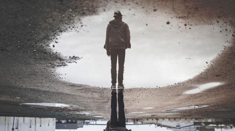 Person reflection in a puddle on the pavement